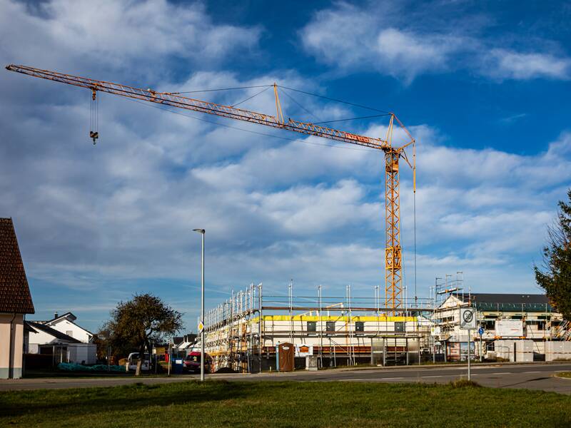 Ein gelber Baukran bei einer Baustelle für ein Haus.